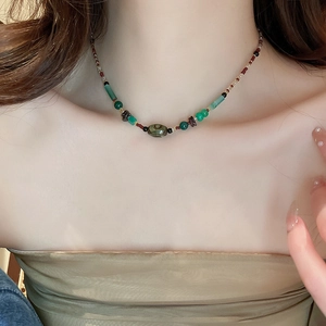 Gros plan d'un collier ras du cou ethnique avec perles vertes et pierre à motif oeil