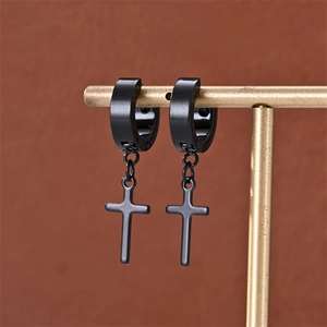 Detail of black cross drop earrings in matte stainless steel on a golden display stand