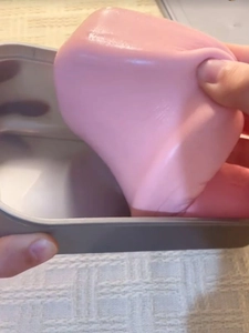 Detailed view of pink slow rising squishy toy being stretched from its grey storage box