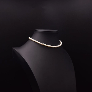 Elegant natural white pearl choker necklace displayed on a black neck bust model