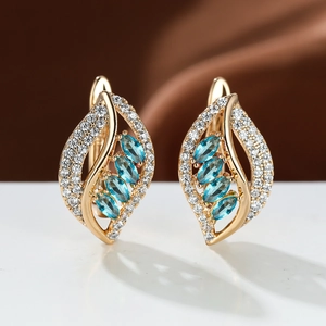 Close-up of champagne gold leaf earrings with light blue gems and zircon stones