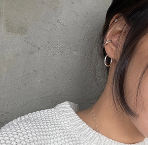 Close-up of minimalist 925 silver ear cuffs and hoop earrings styled on ear with a chain