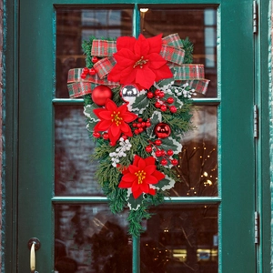 Christmas teardrop swag with red poinsettias, plaid bow, and berries on a vintage door