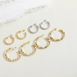 Detailed set of textured gold and silver hoop earrings with colorful zircon stones on stone