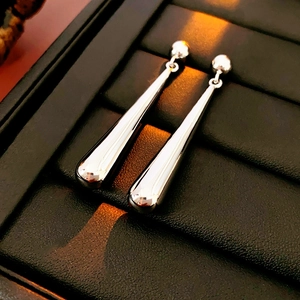 Macro detail of silver teardrop earrings with high-gloss finish in black jewelry box