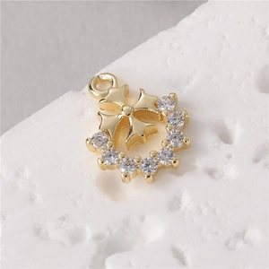 Golden cross wreath pendant with sparkling zircons on textured white background