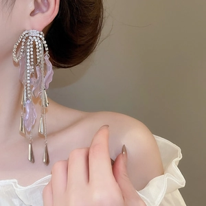 Detail of silver bow tassel earrings with lavender crystals on a female model