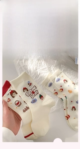 Gros plan de chaussettes en coton crème avec d'adorables filles de dessin animé et nœuds rouges