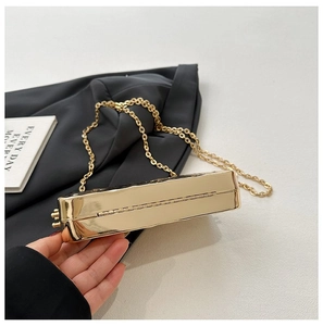 Detail view of gold metallic evening bag with polished surface and link chain
