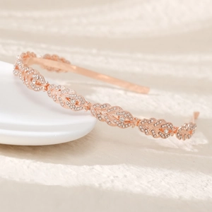 Detailed view of a rose gold leaf-shaped headband with crystals on a ceramic plate