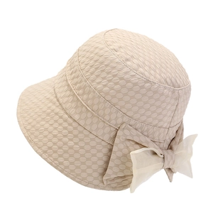 Detailed view of beige sun hat with textured fabric and large sheer bow decoration