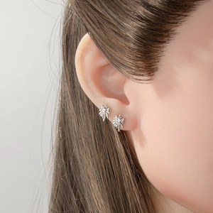 Silver starburst helix piercing earrings with micro-inlaid zircon worn by a female model