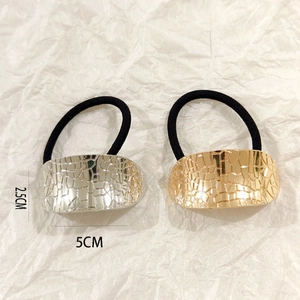 Detail of silver and gold hollow metal hair ties with textured pattern on black elastic