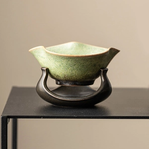 Retro kiln-changed ceramic tea strainer with a rustic green glaze and metallic stand