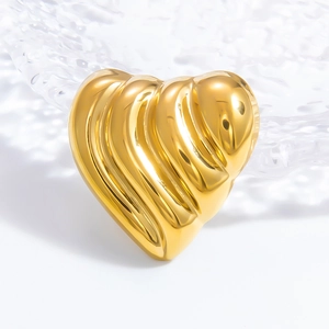 Macro shot of a golden heart ring with pleated metal texture on a glass tray