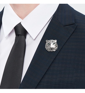 Detail of silver tiger brooch with green stone eyes on a navy blue suit lapel