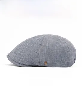 Détail de la casquette gavroche grise montrant le tissu texturé et l'emblème latéral