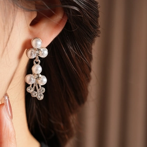 Détail des boucles d'oreilles de mariée en argent avec perles et strass brillants