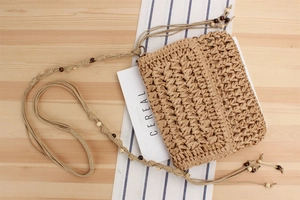 Close-up of Bohemian straw crossbody bag with natural weave and decorative wooden beads