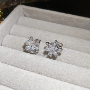 Macro detail of silver snowflake zircon earrings on grey velvet jewelry box padding