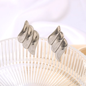 French retro silver angel wing earrings displayed on a glass plate with white silk
