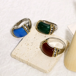 Detailed view of three vintage-style titanium steel rings with colored gemstones on stone