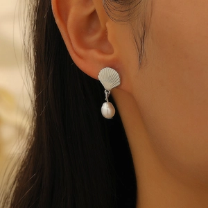 Vista detallada de pendientes de concha plateados con perlas usados por una modelo