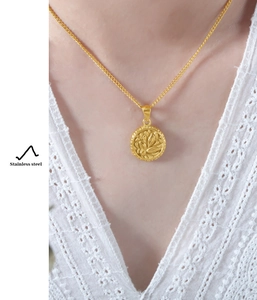 Golden round floral pendant necklace in stainless steel worn over white lace dress
