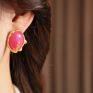 Gros plan d'une boucle d'oreille vintage dorée avec résine magenta sur un mannequin