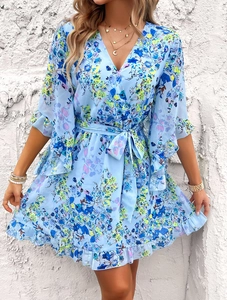 Detailed close-up of blue floral chiffon dress with V-neckline and waist tie detail