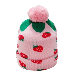 Close-up of pink knitted hat with red strawberry patterns, green leaves and a top pompom