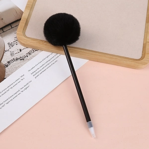 Detail shot of a creative black ballpoint pen with a soft decorative faux fur pom pom top