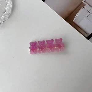 Detail of four gummy bear hair clips in pink and purple with glitter matte finish