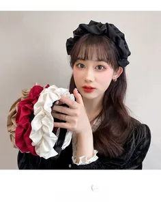 Détail de bandeaux en satin froncé noir, beige, rouge et ivoire pour un look de cheveux rétro