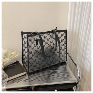 Close-up of transparent PVC tote bag featuring black M-pattern monogram and leather trim