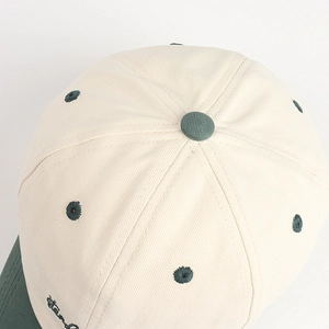 Gros plan des coutures contrastées et broderies sur la casquette en coton