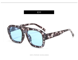 Detail view of oversized square sunglasses with grey tortoiseshell frames and blue lenses