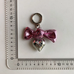 Top view of pink bow keychain with silver heart pendant measured against a scale