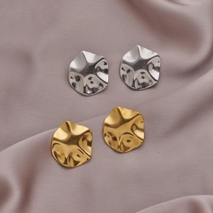 Detailed view of irregular hammered wave disk earrings in gold and silver finishes