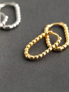 Macro shot of U-shaped gold beaded earrings in S925 sterling silver minimalist style