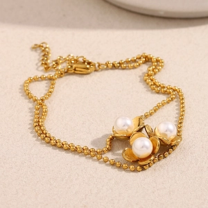 Detail of double-layer gold bead chain featuring triple pearl flower charms and clasp
