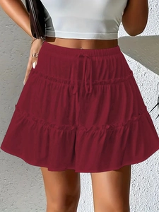 Detail view of tiered dark red mini skirt with drawstring waist and ruffle layers