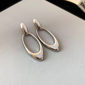 Detailed view of silver oval geometric earrings with polished metal mirror finish