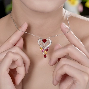 Luxury silver heart necklace with vibrant red and yellow gemstones on model's neck