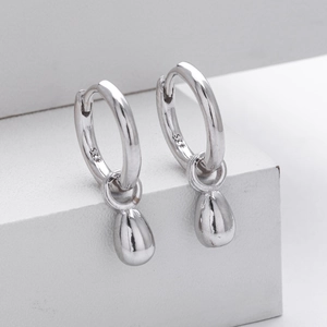 Macro view of polished S925 sterling silver hoop earrings with waterdrop-shaped pendants