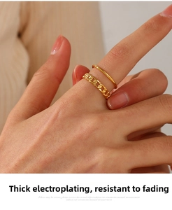Detail of layered gold-plated chain ring and minimalist band on a female hand