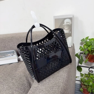 Detail of black hollow-out silicone tote bag with retro mesh pattern on a sofa
