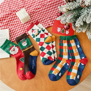 Detailed view of red Santa Claus and plaid cotton Christmas socks in a gift box setup