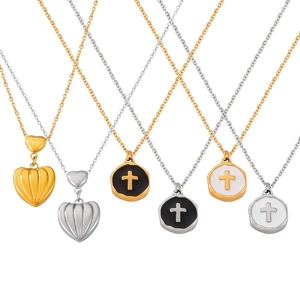 Gold and silver heart and cross pendants on thin steel chains against a white background