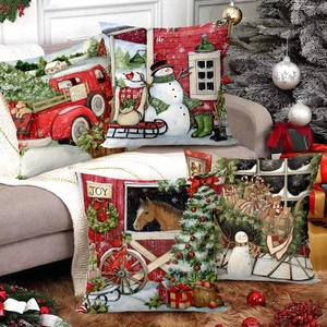 Set of four Christmas pillow covers with festive snowman and red truck prints on a sofa